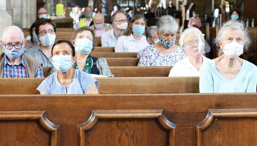Gläubige mit Maske in Kirchenbänken
