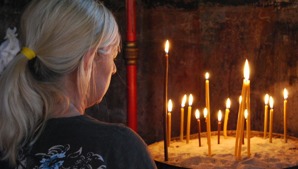 Gläubige vor Kerzen in einer orthodoxen Kirche