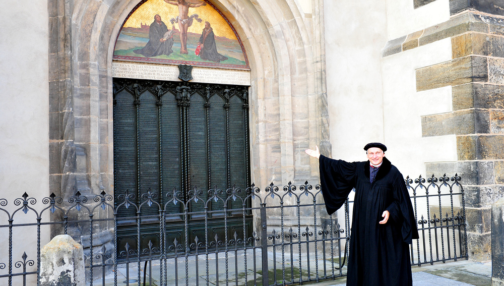 Martin Luther (Kirchenmeister Bernhard Naumann) vor dem Tor der Schlosskirche Wittenberg