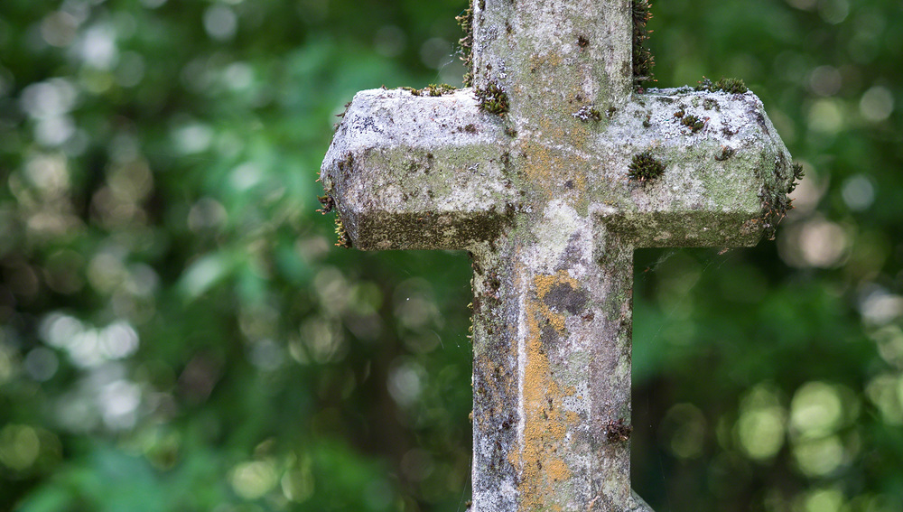 Ein steinernes Kreuz auf einem Friedhof. Ruhe und Andenken an die Verstorbenen.
