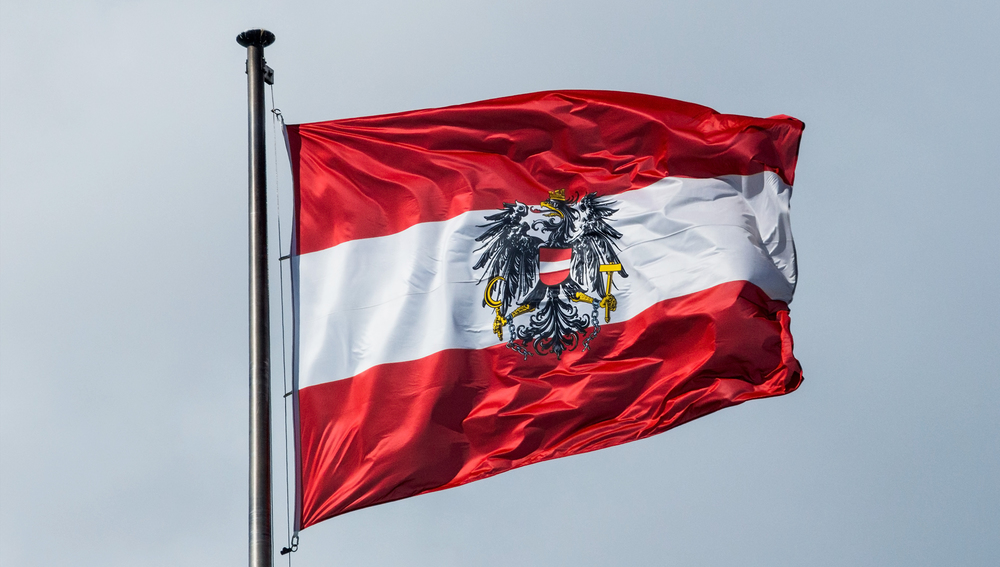 Die österreichische Fahne weht im Wind vor blauem Himmel. Flagge Österreich