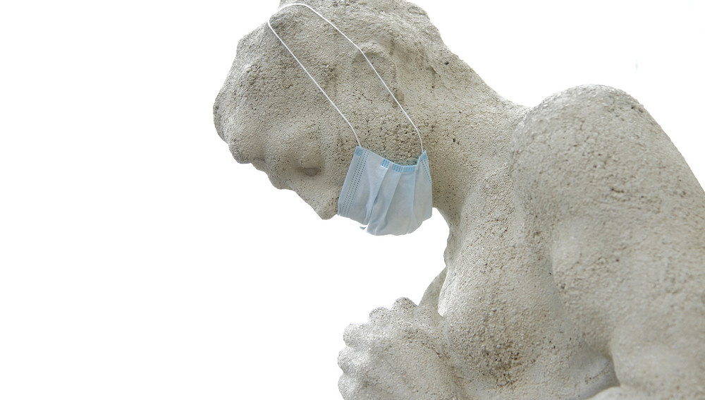 Statue eines betenden Menschen mit Mundschutz                      