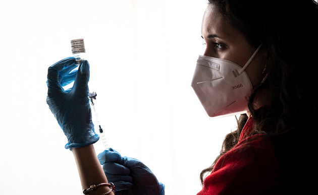 Eine Frau zieht eine Spritze auf mit dem Impfstoff gegen das Coronavirus